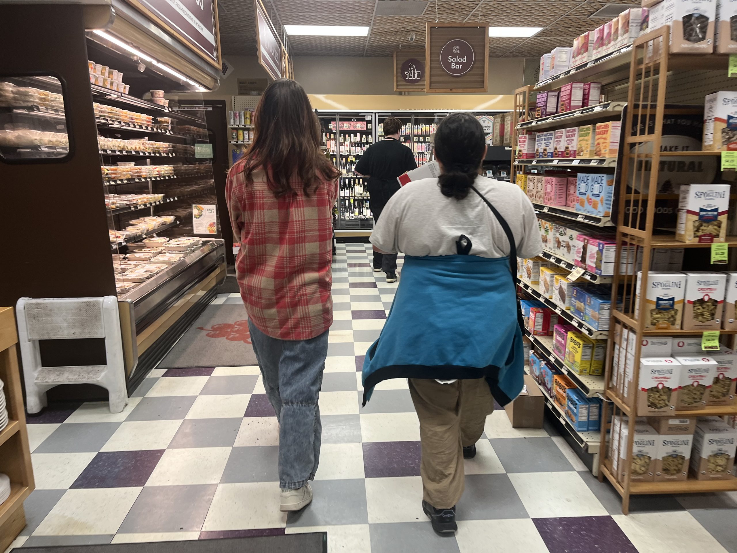 Intern in Commonwealth Autism Career Readiness and Employment program walking alongside Job Coach in Good Foods Grocery aisle