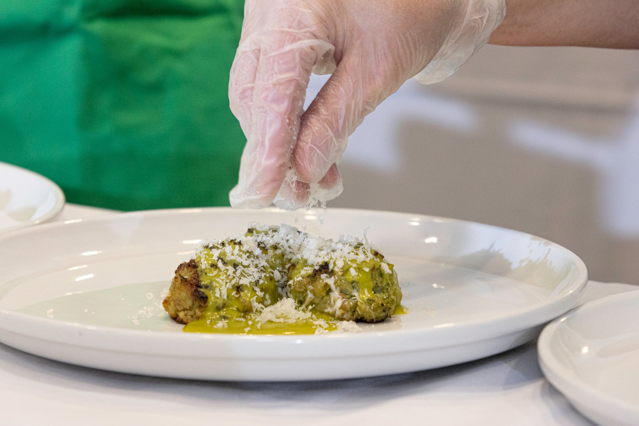 a chef adds garnish to a finished dish on a plate during the commonwealth autism richmond 2024 coaches cook off